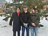 Tre menn foran et juletre på et torg.