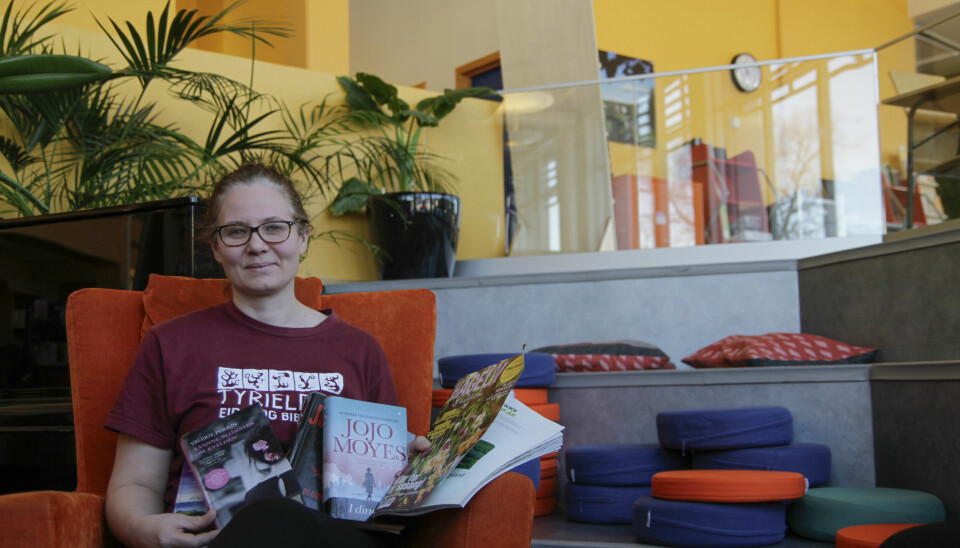Ingunn Espeland ved Tyrielden Eidskog bibliotek er gleder seg over alle utlån i 2023. Her sitter hun med noen av de mest populære bøkene og tidsskrift.